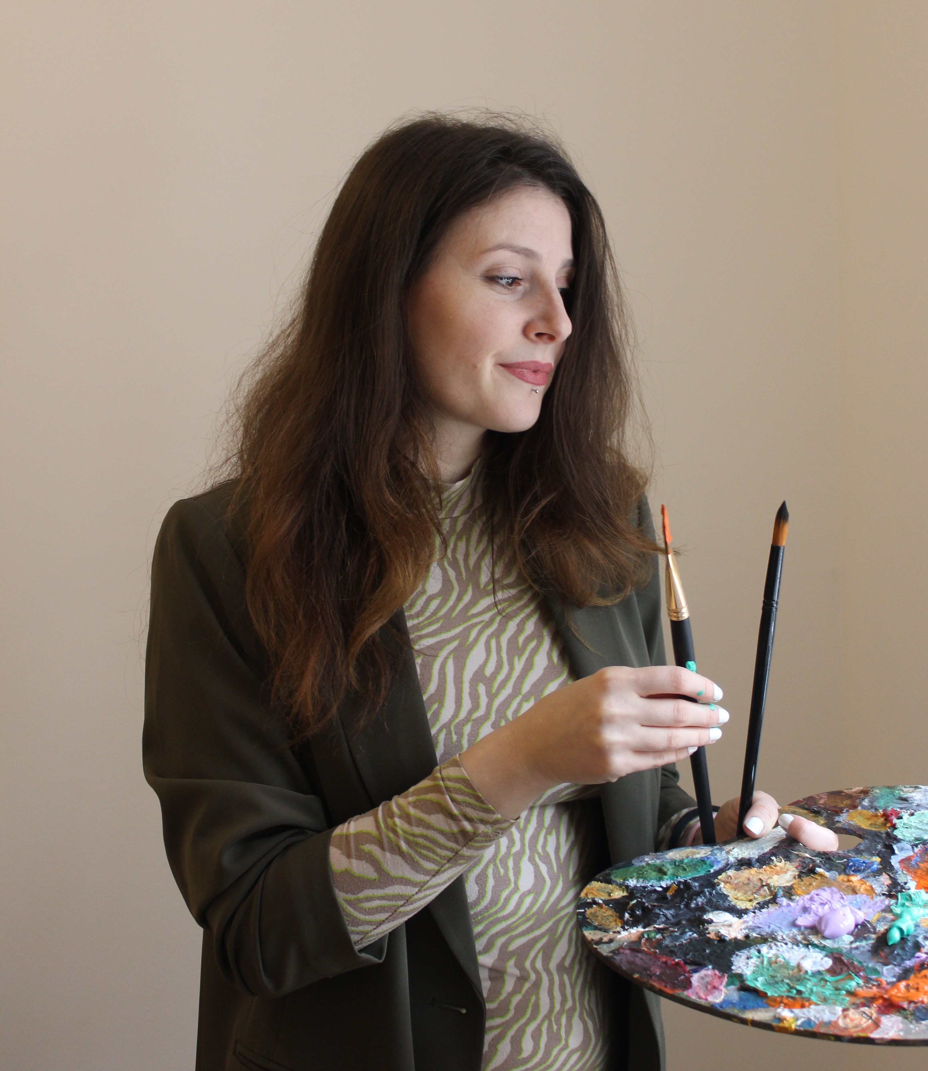 Sara Milojević holding paintbrushes in her studio