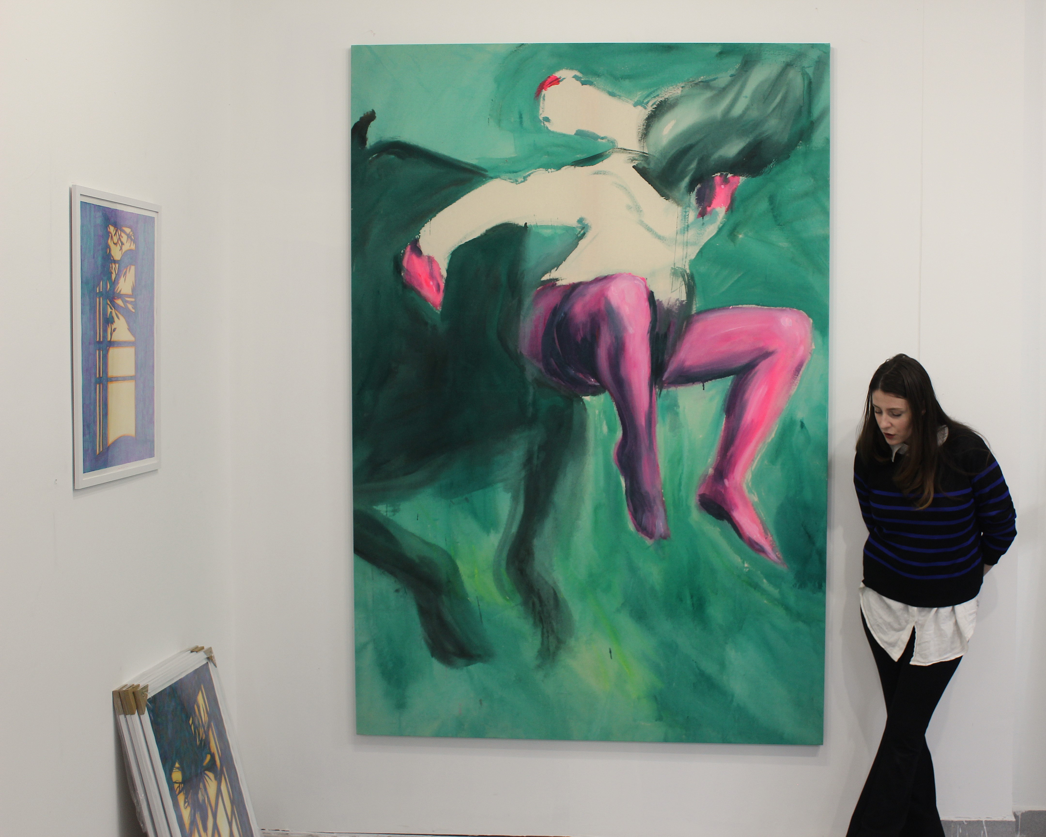 Sara Milojević standing beside a large green and pink painting in her atelier